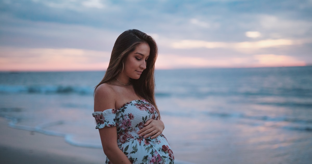 Gravid kvinna vid havet i klänning
