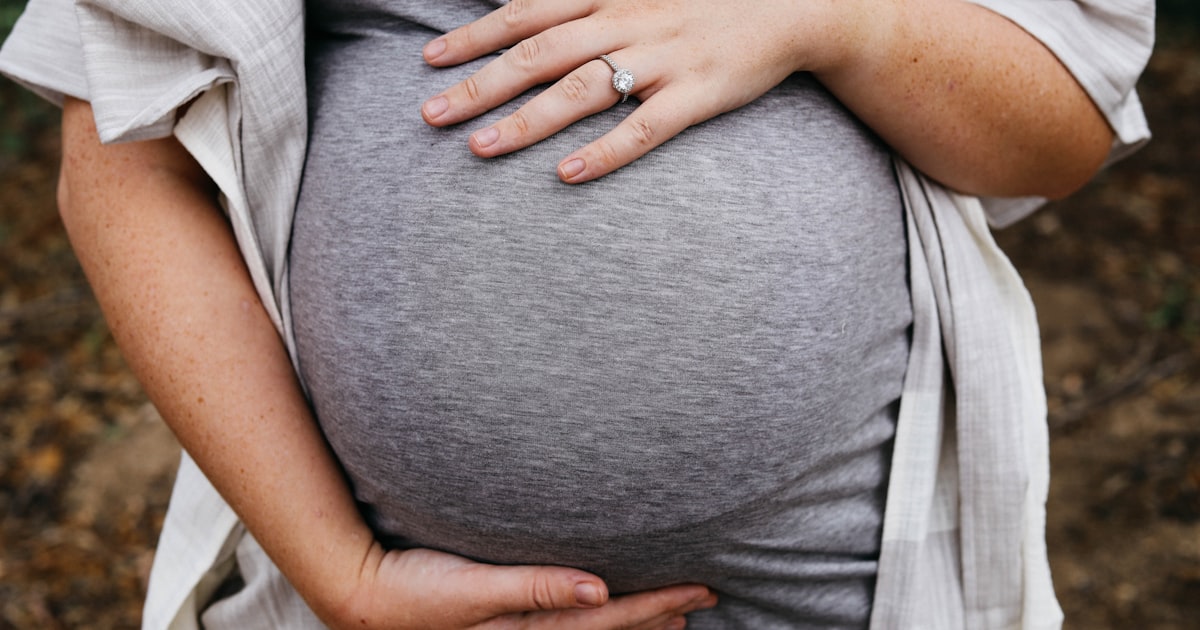 Gravid kvinna håller om magen – tidig graviditet