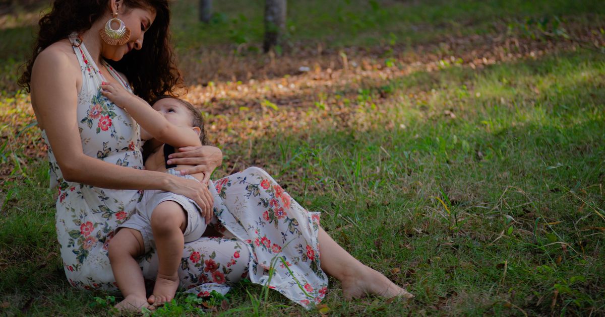A mother lovingly breastfeeding her child in a peaceful outdoor setting.
